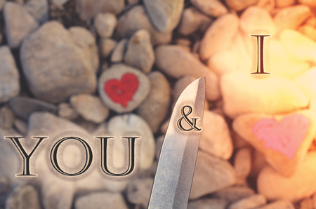 Cutting knife diving pink heart painted with lipstick on piece of stone. Symbol of the end of love and of two people break up and divorce with text letter Heart attack You and Iの写真素材