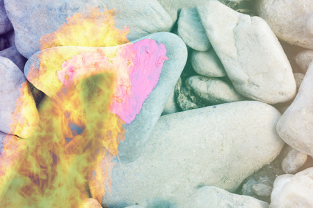 Cutting fire diving pink heart painted with lipstick on piece of stone. Symbol of the end of love and of two people break up and divorceの写真素材