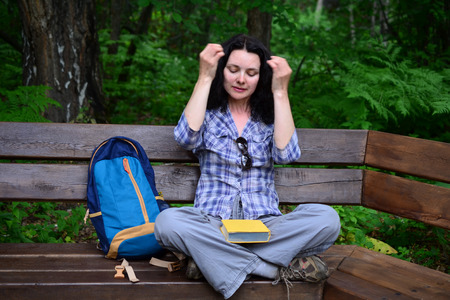 Traveling woman reading book and relaxing at park. Concept of freelance work and study during vacationの写真素材