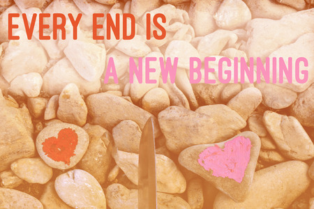 Cutting knife diving pink heart painted with lipstick on piece of stone. Symbol of the end of love and of two people break up and divorce with text letter Every end is new beginningの写真素材