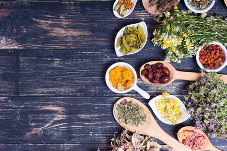 Herbs , berries and flowers on color wooden table backgroundの写真素材