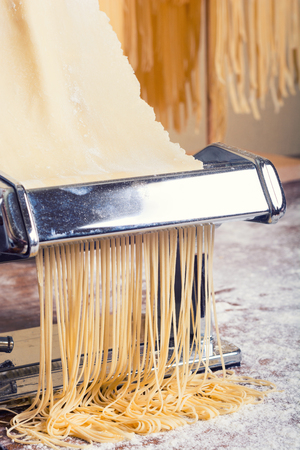 fresh pasta and pasta machine on kitchen tableの写真素材