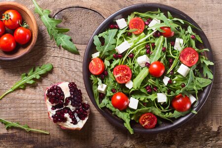 Fresh spring salad with rucola , feta cheese , tomatoes and pomegranate seedsの写真素材
