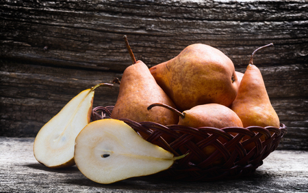 Pears in basket on wooden backgroundの写真素材