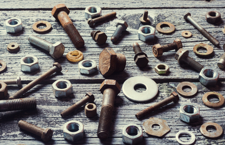 old photo of nuts and bolts on wooden backgroundの写真素材