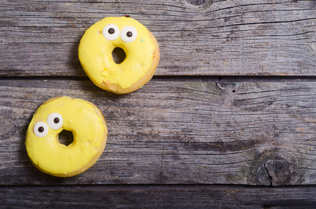 Colorful funny donuts on wooden background . Top viewの写真素材