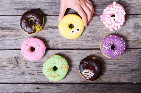Colorful baked donuts in woman handの写真素材