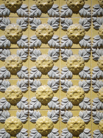 A piece of an old yellow floral ceramic tile in Portugal on the walls of housesの写真素材
