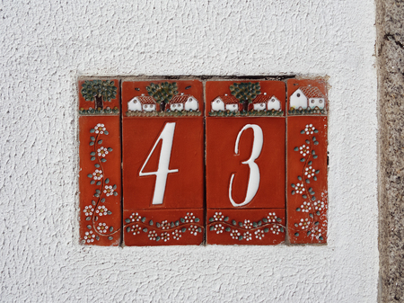 Tiled red house number 43 on the white stucco wallの写真素材