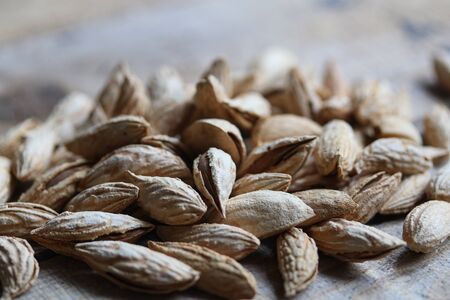 almonds in the shells on a wooden table close up