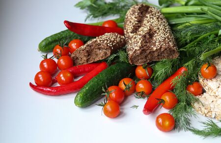ripe tomatoes, chili peppers, cucumbers, bread and herbs on a white background close-upの写真素材