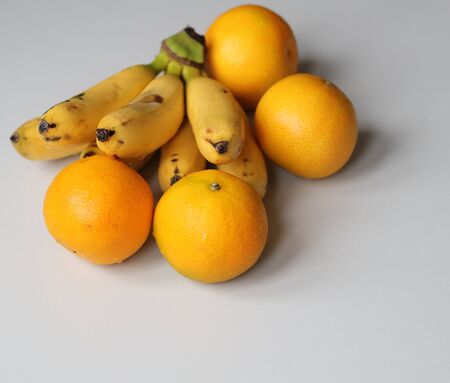 ripe bananas and oranges on a white background close upの写真素材