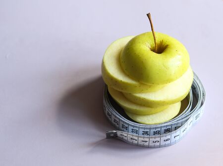 sliced apple and measuring tape on a light background close upの写真素材