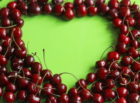 ripe cherries on a green background laid out in the shape of a heart