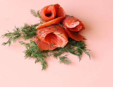 slices of salted salmon and dill on a pink background close upの写真素材