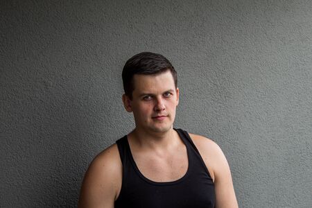 Young, strong guy. An inquisitive look, as if he wants to ask something. Grey background.