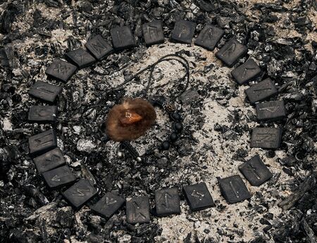 Circle of 24 Norse runes stones with viking amulet inside on ashes backgroundの写真素材
