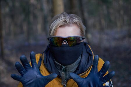 The masked girl in glasses shows her hands in gloves. Outdoor. Protection against virus conceptの写真素材