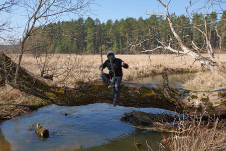 Guy is fishing on the tree in nature wearing a protection face mask, in coronavirus COVID-19...