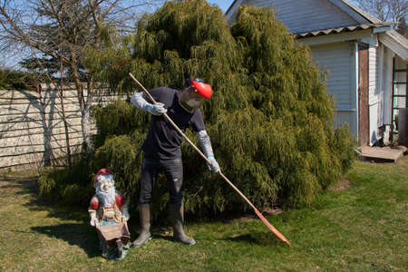 Man gardening in his garden, wearing a protection face mask, in coronavirus COVID-19 pandemic.のeditorial素材