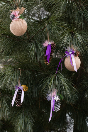 Beautiful Christmas tree decorated with handmade toys. Spruce cones, decorated with ribbons, beads, fabric. Outdoors.の写真素材