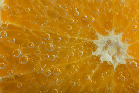 Slice of bright ripe orange in sparkling water. There are many gas bubbles on the surface. Natural citrus background. Macro. Wallpaper.の写真素材