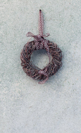 Easter decoration. Rustic natural wreath of birch branches with a brown ribbon with white polka dots. Background of old chipboard with remnants of green paint, space for an inscription. Spring.の写真素材