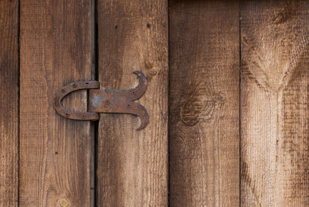 An old wooden barn door element features a textured surface and a rusty metal hinge. This vignette captures the rustic charm and timeless character of vintage craftsmanship.の写真素材