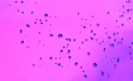 Abstract texture of water drops over pink background. Close-up of drop bubbles. Top view of...