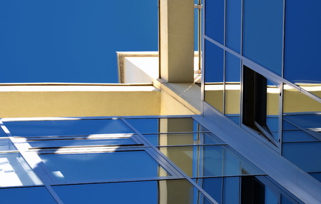 Abstract glass background in blue and yellow colors. Architectural detail. Surface of skyscraper on sky backdrop.の写真素材