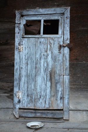 Old door with rusty lock. Near door standing a dirty ceramic plate. Concept: dilapidated, old time, breakdown, destructionの写真素材