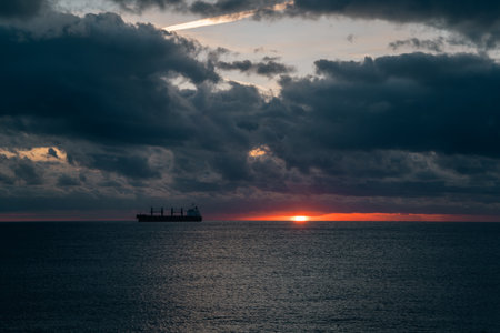 ship profile over tranquil waters at sunrise, freight vessel shape during peaceful morning on sea,...