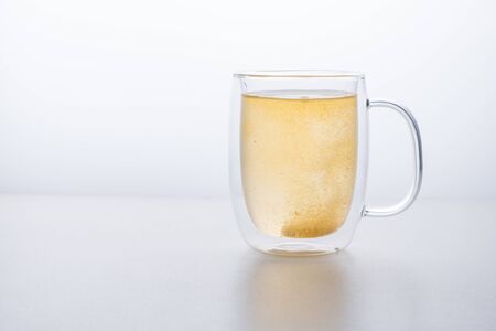 glass thermo mug of water-soluble effervescent orange tablet on a white table