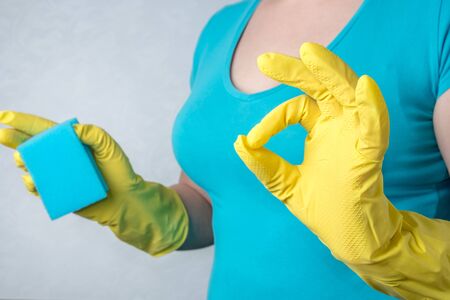 woman in yellow rubber gloves showing gesture OK. The concept of spring cleaning, skin protection...
