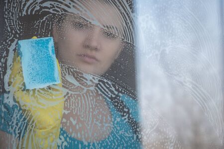 housewife in yellow gloves washes the windowの写真素材