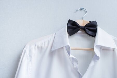 white mens shirt and black bow tie on a hanger