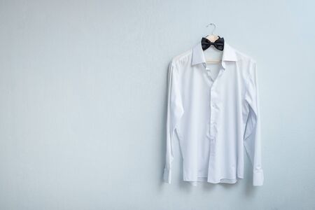 white men's shirt and black bow tie on a hanger. concept: pop modern sale. preparing the groom for the weddingの写真素材