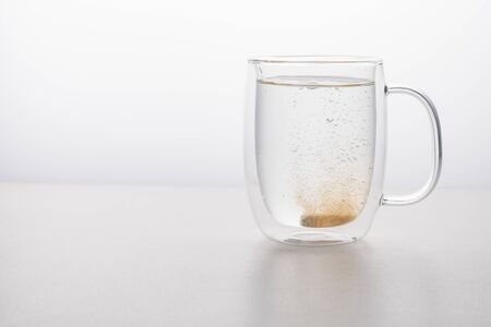 glass thermo mug of water-soluble effervescent orange tablet on a white tableの写真素材