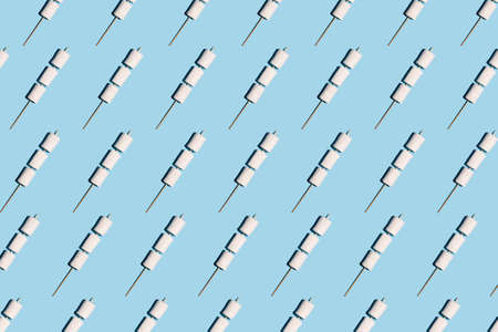 Pattern of white marshmallows strung on a skewer on a blue backgroundの写真素材