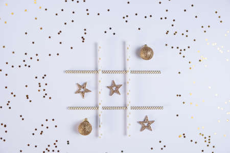 Party decorations in white and gold colors. A field for playing tic-tac-toe made of paper tubes for a cocktail with Christmas balls and stars laid out in clutchesの写真素材