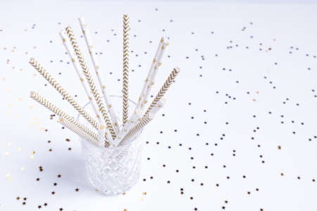 Party decorations in white and gold colors. Crystal glass with paper cocktail tubesの写真素材