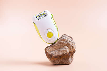 levitating epilator for hair removal on a stone stand and beige background. Self-care in a modern presentation with natural colors and natural materialsの写真素材