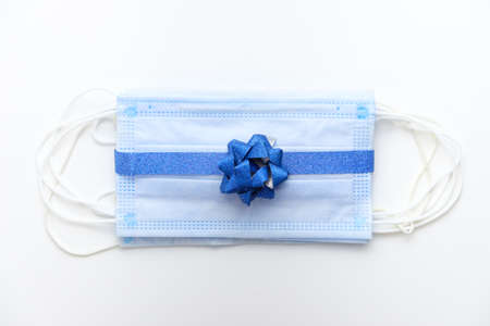 Protective masks tied with a shiny blue ribbon with a blue bow. Christmas present new year during the coronavirus pandemicの写真素材