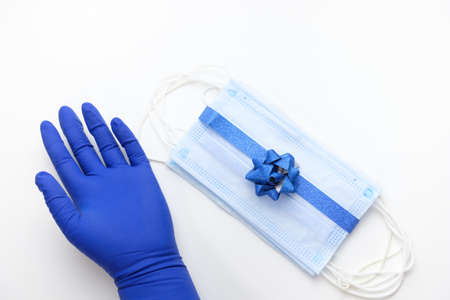Protective masks tied with shiny blue ribbon with blue bow and blue gloves. Christmas or New year present during the coronavirus pandemicの写真素材