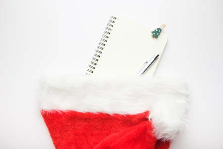 The notebook and pen are hidden in the Santa Claus hat. Office for writing plans for the new year or...