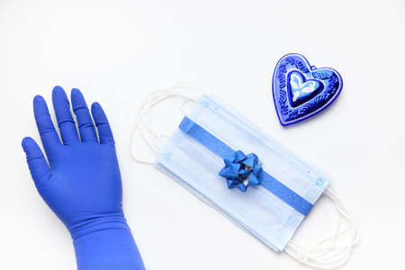 Protective masks tied with shiny blue ribbon with blue bow and Christmas decorations and blue gloves. Christmas or New year present during the coronavirus pandemicの写真素材