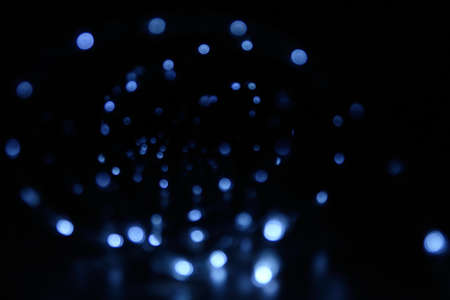 Blurred background with a cool blue glow in the dark. Glowing Christmas garland in bokeh. Blank for the background.の写真素材