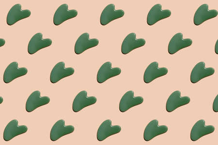Pattern of gua sha massagers made of jade against a beige background. Are modern tools for skin care. Pattern for the beauty industryの写真素材