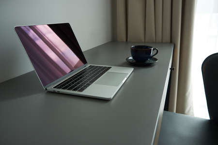 Home Office. Convenient workplace at home or hotel. Laptop on the desktop and a cup of tea or coffee. Mobile minimalistic work officeの写真素材