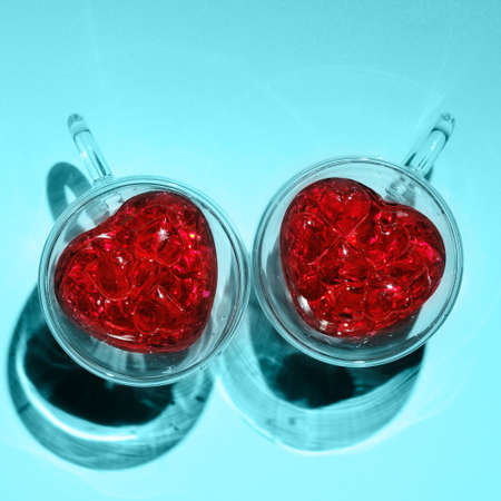Image for valentines day. Two glass mugs in the shape of hearts in bright light.の写真素材